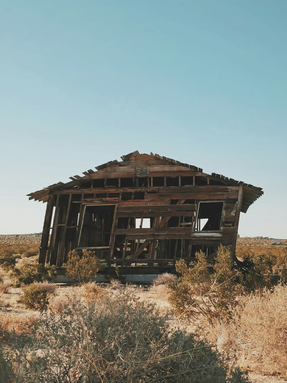 Casa de madera marrón en campo de hierba marrón bajo el cielo azul durante el día