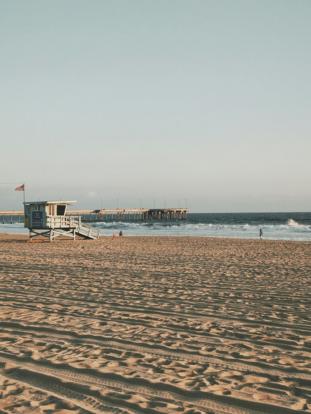 昼間のビーチにある白い木造のライフガードハウス