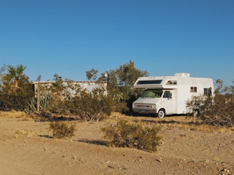 white and brown rv on brown field under blue sky during daytime