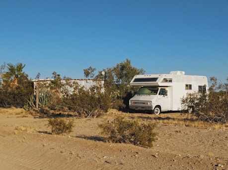 white and brown rv on brown field under blue sky during daytime