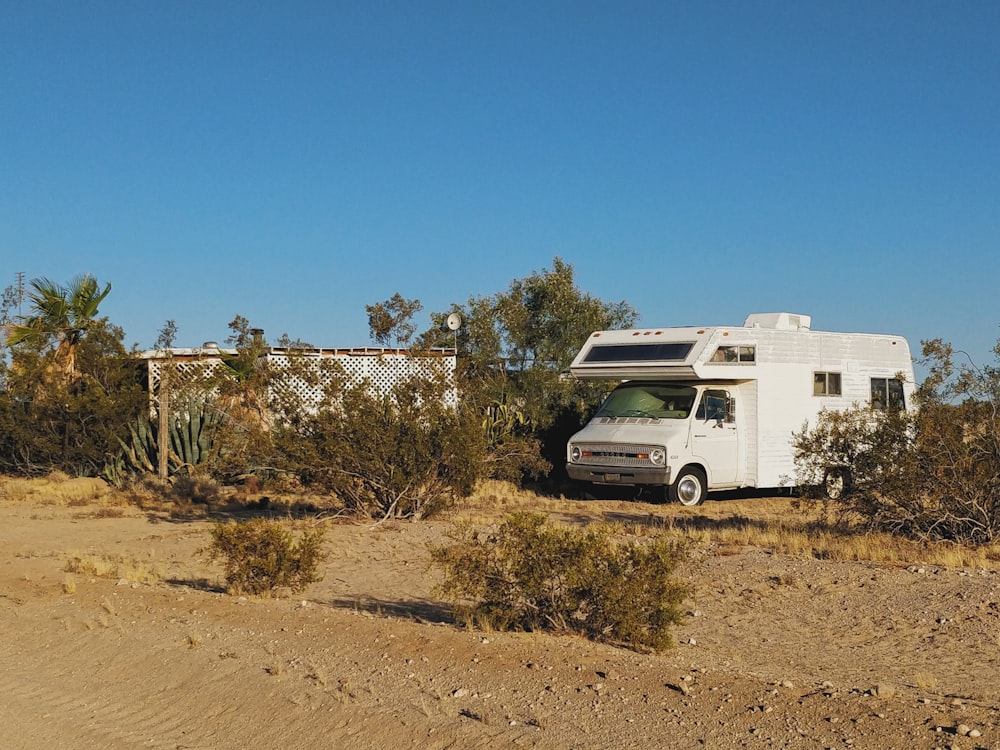 white and brown rv on brown field under blue sky during daytime