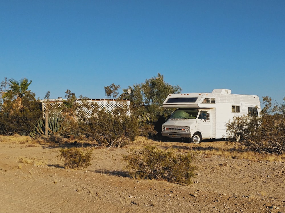 Camping-car blanc et brun sur un terrain brun sous un ciel bleu pendant la journée