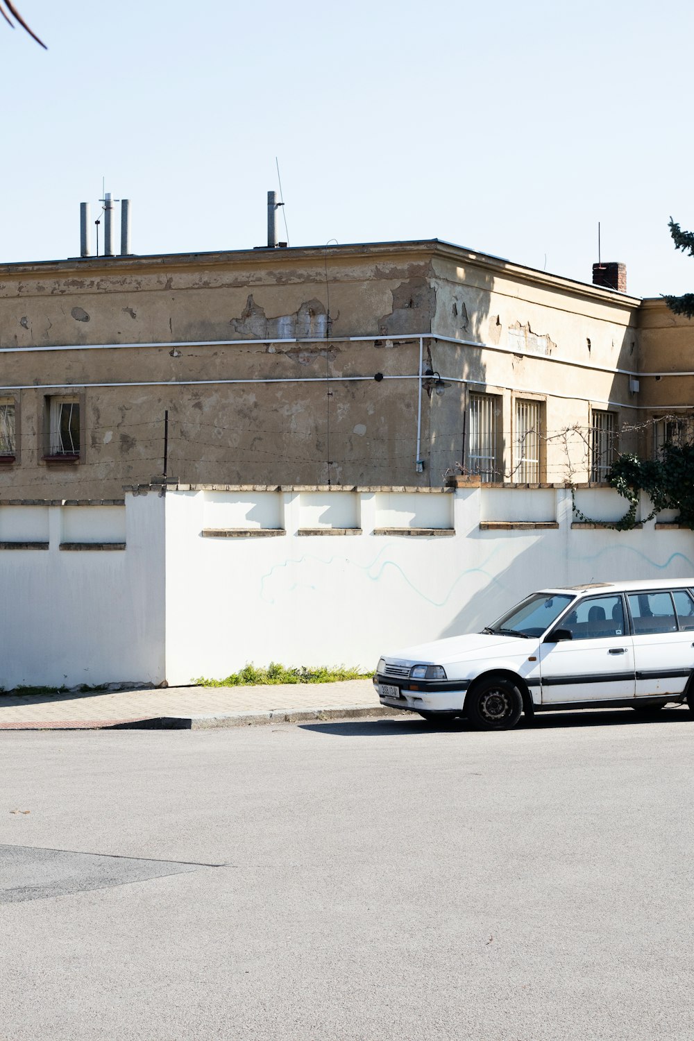 white sedan parked beside white concrete building during daytime