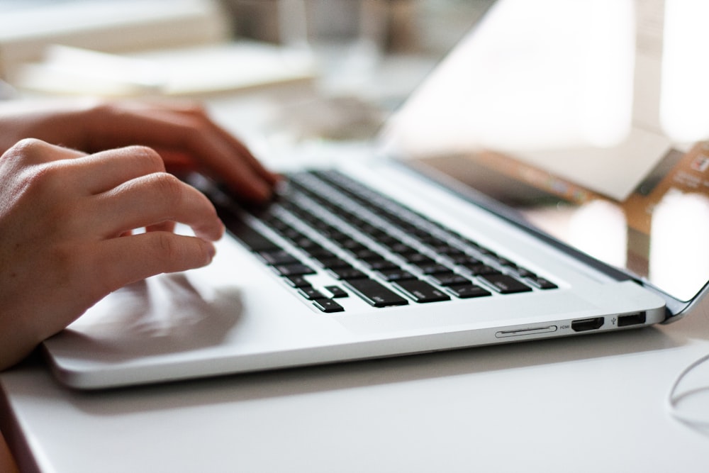 person using macbook pro on white table