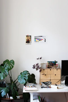 A bright workspace with sketches and plants on a wooden desk.
