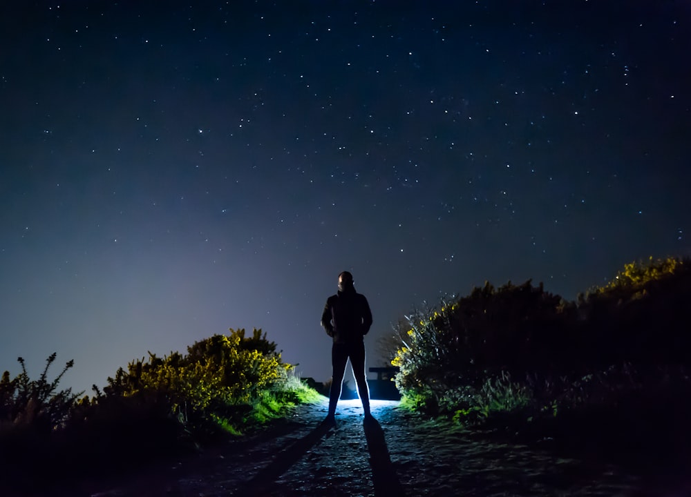 man in black jacket standing on pathway during night time