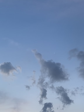 A serene sky with soft pale blue clouds gently drifting, evoking calm and creativity.