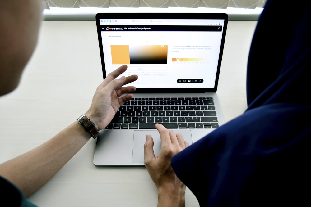 person using macbook pro on white table