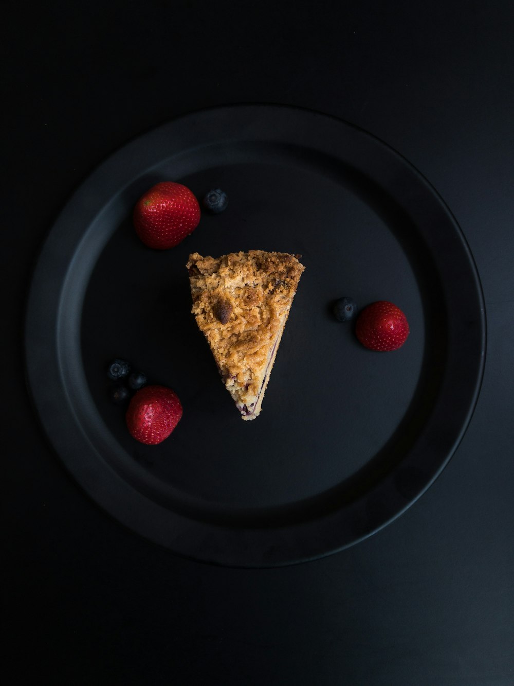 brown bread with red and black berries on black round plate