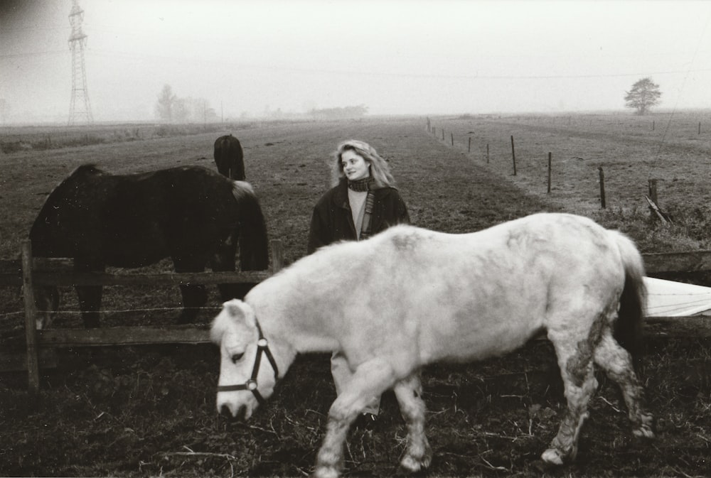 grayscale photo of woman standing beside horse
