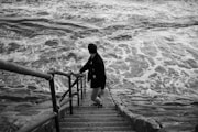 man in black jacket walking on wooden bridge