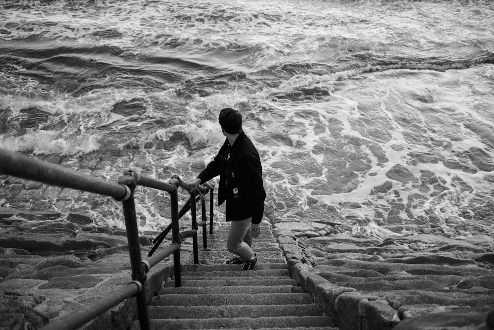 man in black jacket walking on wooden bridge