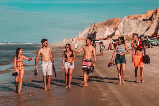 A group of friends walking along a sunlit coastal trail in the Algarve, smiling and chatting.