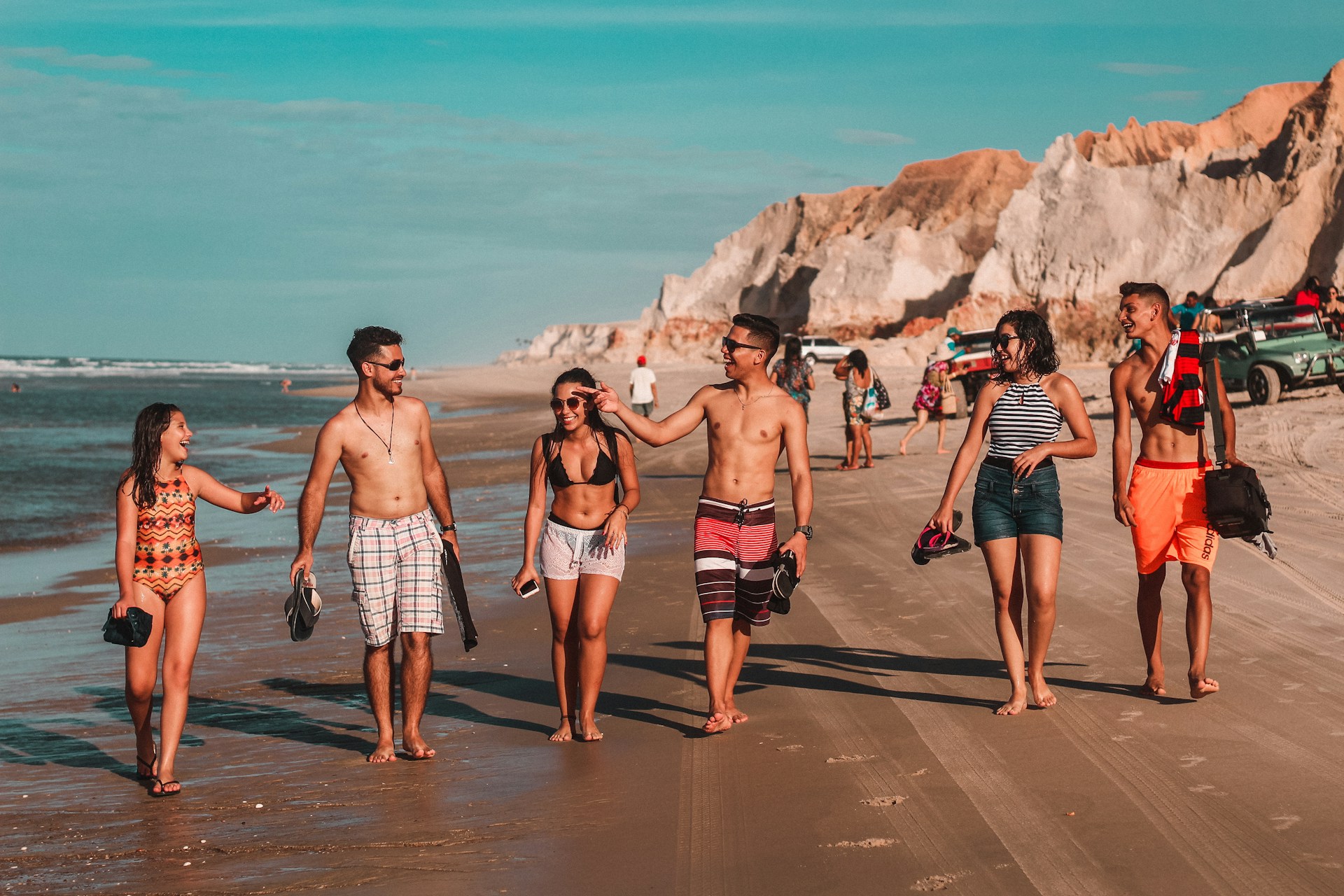 A lively group of travelers laughing together on a sunny beach during a domestic tour organized by Thathwamasi Tours.