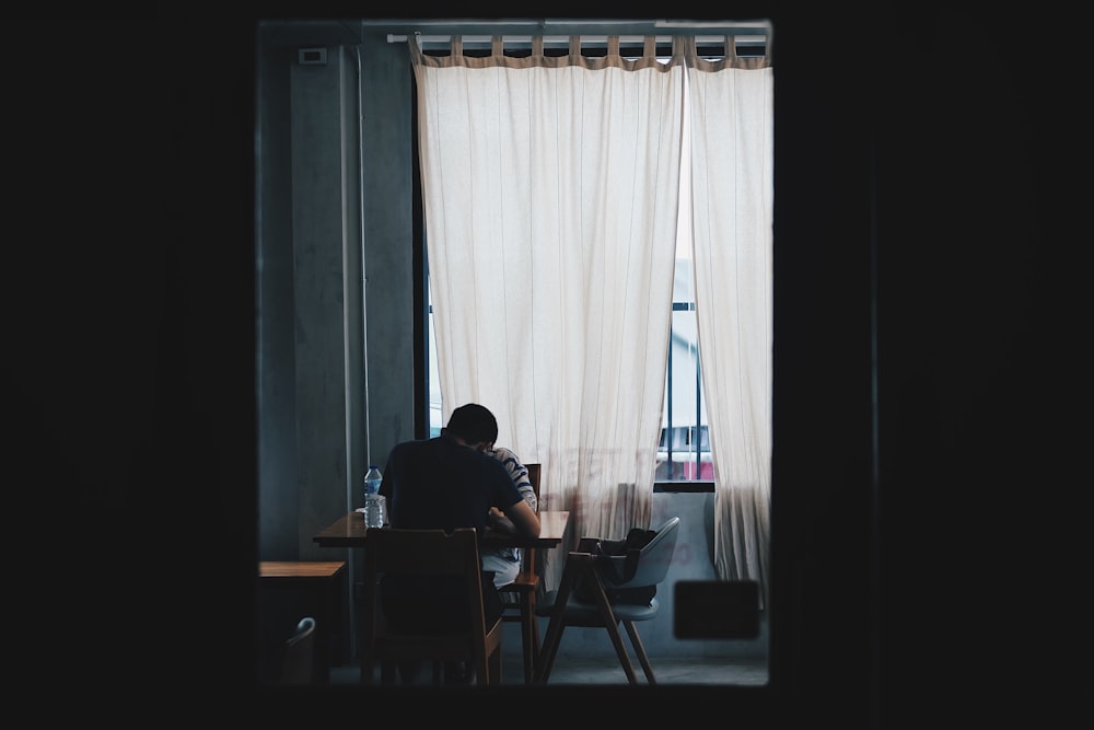 man and woman sitting on chair near window