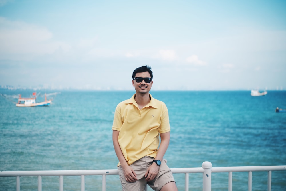 a man sitting on a railing near the ocean