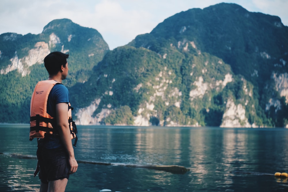 woman in pink shirt standing on rock near body of water during daytime