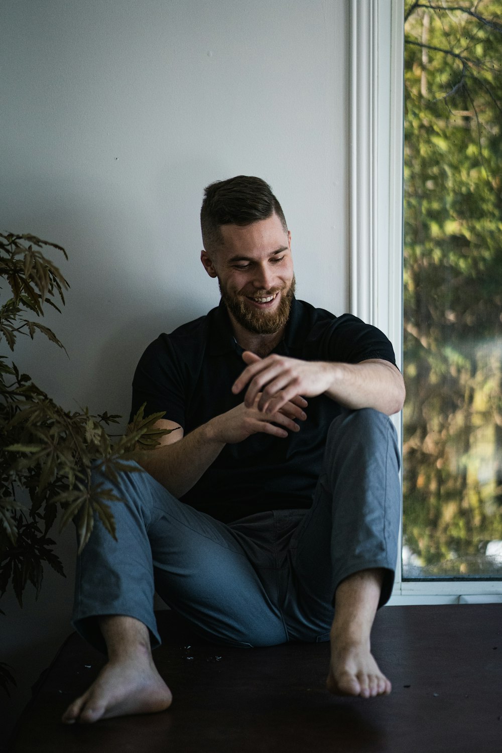 man in black polo shirt sitting on window