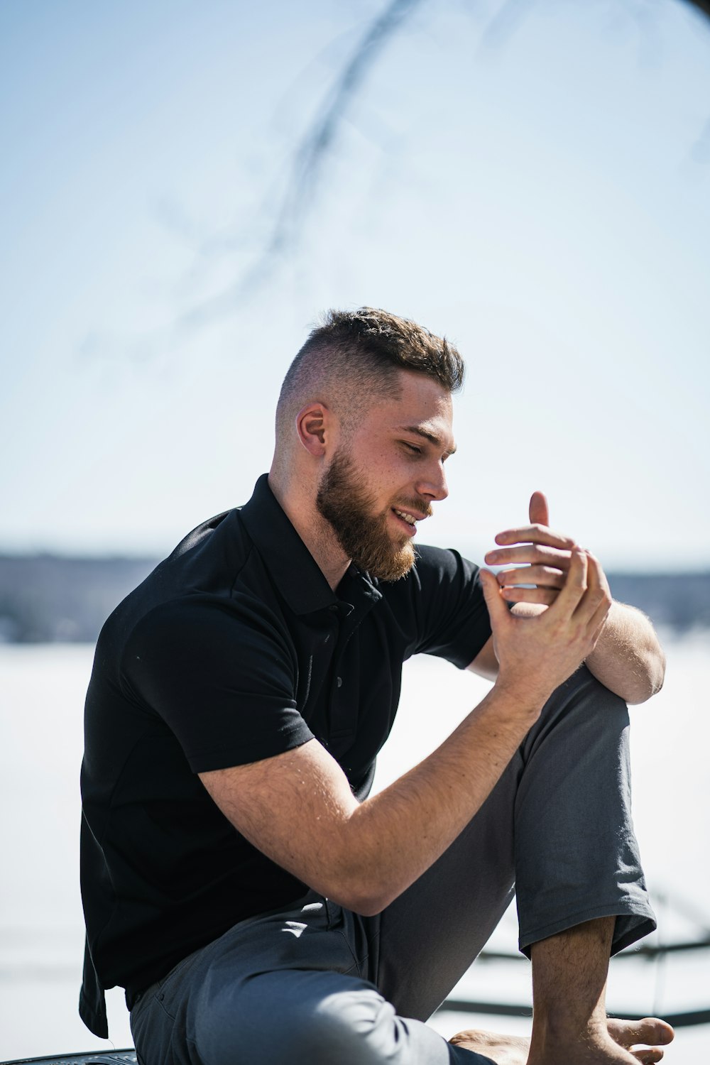 a man with a beard sitting on a ledge