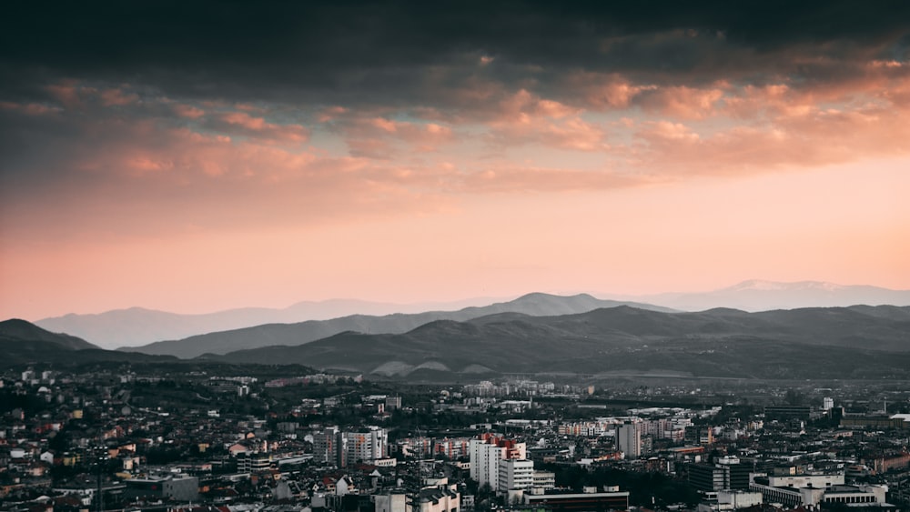 city skyline under orange and gray cloudy sky during sunset