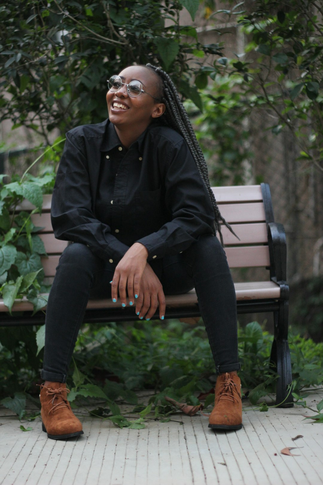 man in black dress shirt and black pants sitting on brown wooden bench