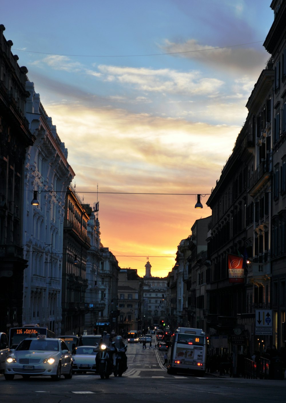 cars parked on street between buildings during sunset