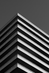 A minimalist black and white photo of a striking modern building with sharp lines and shadows.
