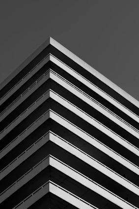 Black and white photo of a sleek, minimalist office building with gradient shadows creating depth.