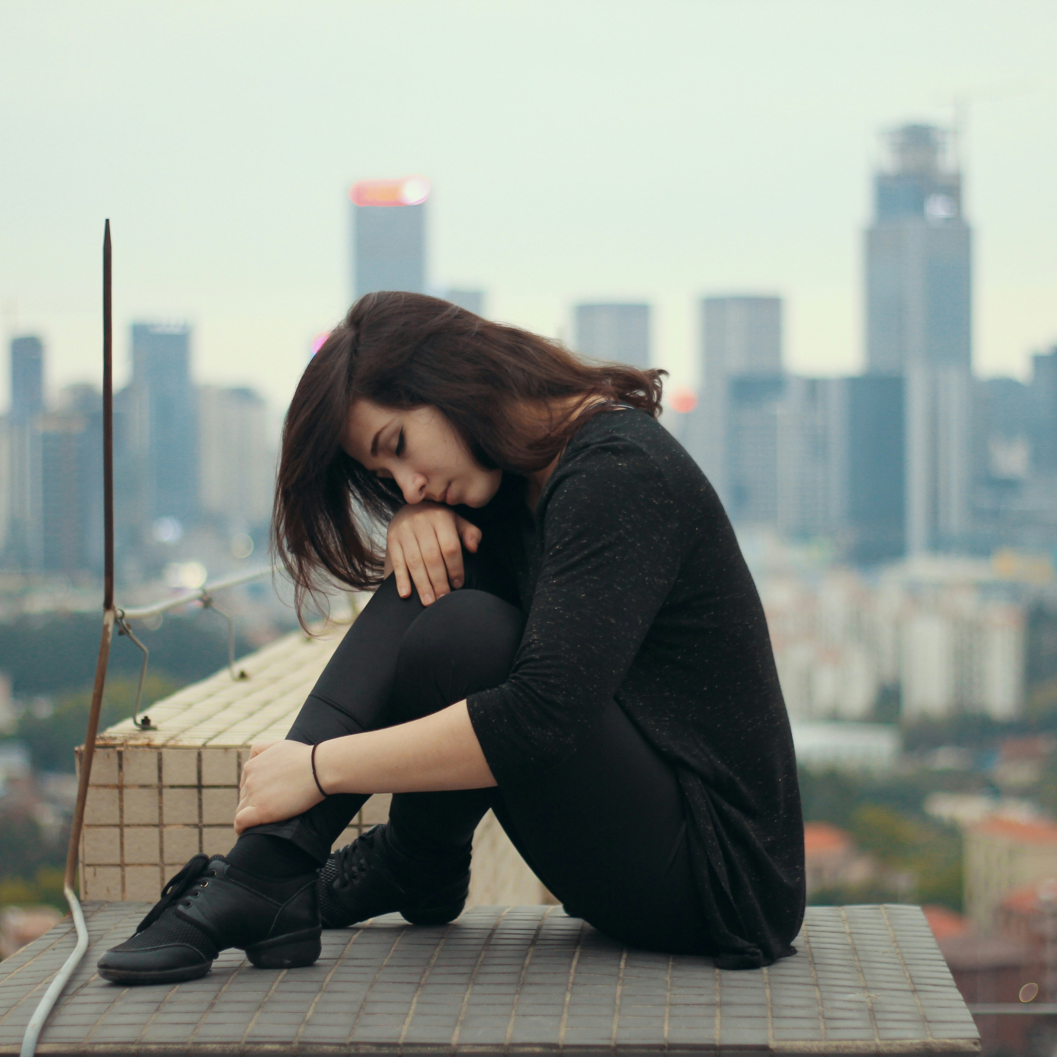 woman in black long sleeve shirt sitting on brown wooden dock during daytime