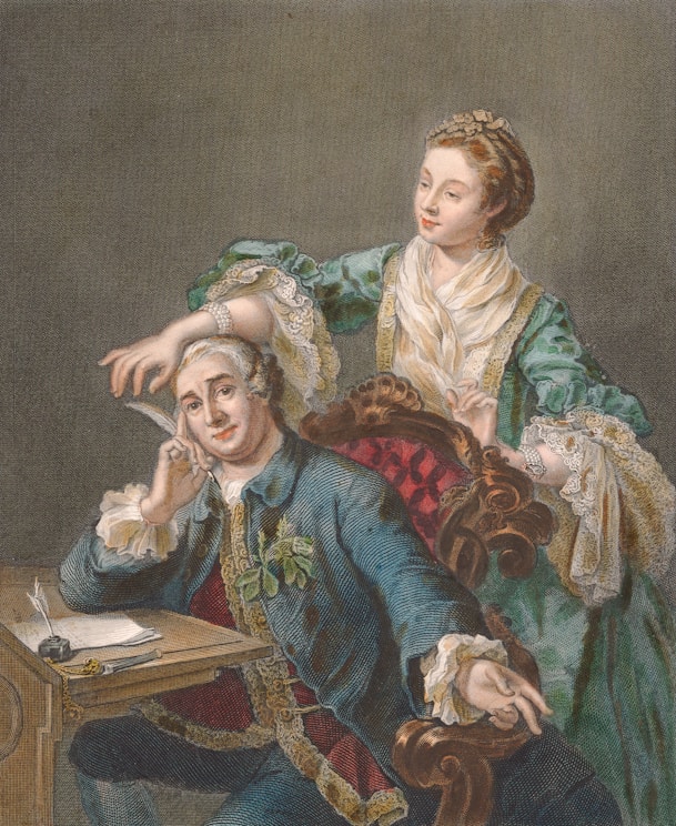 A man in 18th-century attire sits at a wooden desk with a quill in his hand, looking thoughtful. Behind him, a woman dressed in a green gown with elaborate lace and ribbon detailing places her hand gently on his head. The setting suggests a scene from a historical period, with the man's clothing featuring ornate embroidery and a flower pinned to his jacket, while the woman appears to be encouraging or consoling him.
