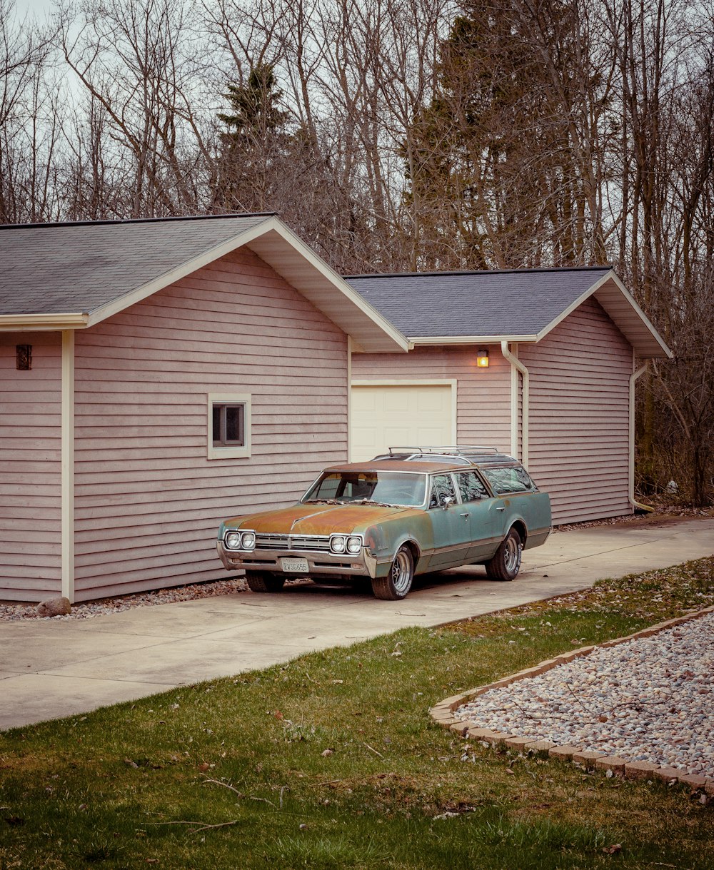 black sedan parked beside white wooden house