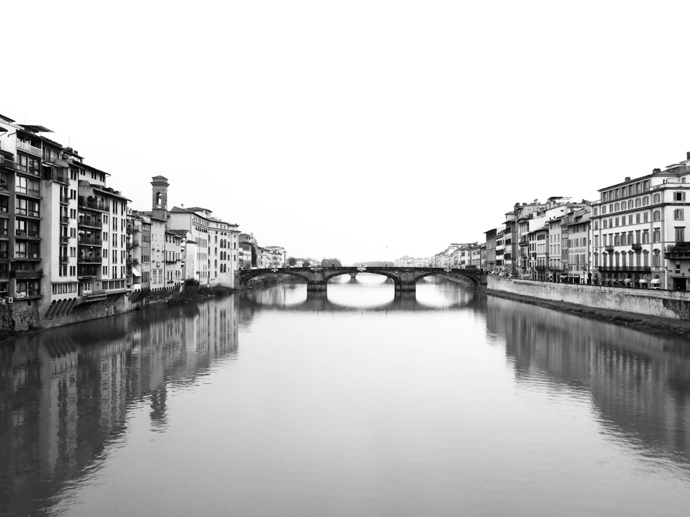 grayscale photo of river between buildings