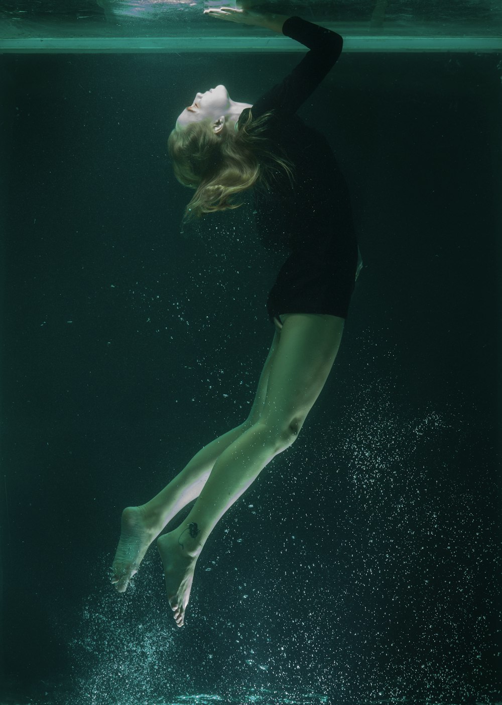 woman in black shirt and green shorts in water