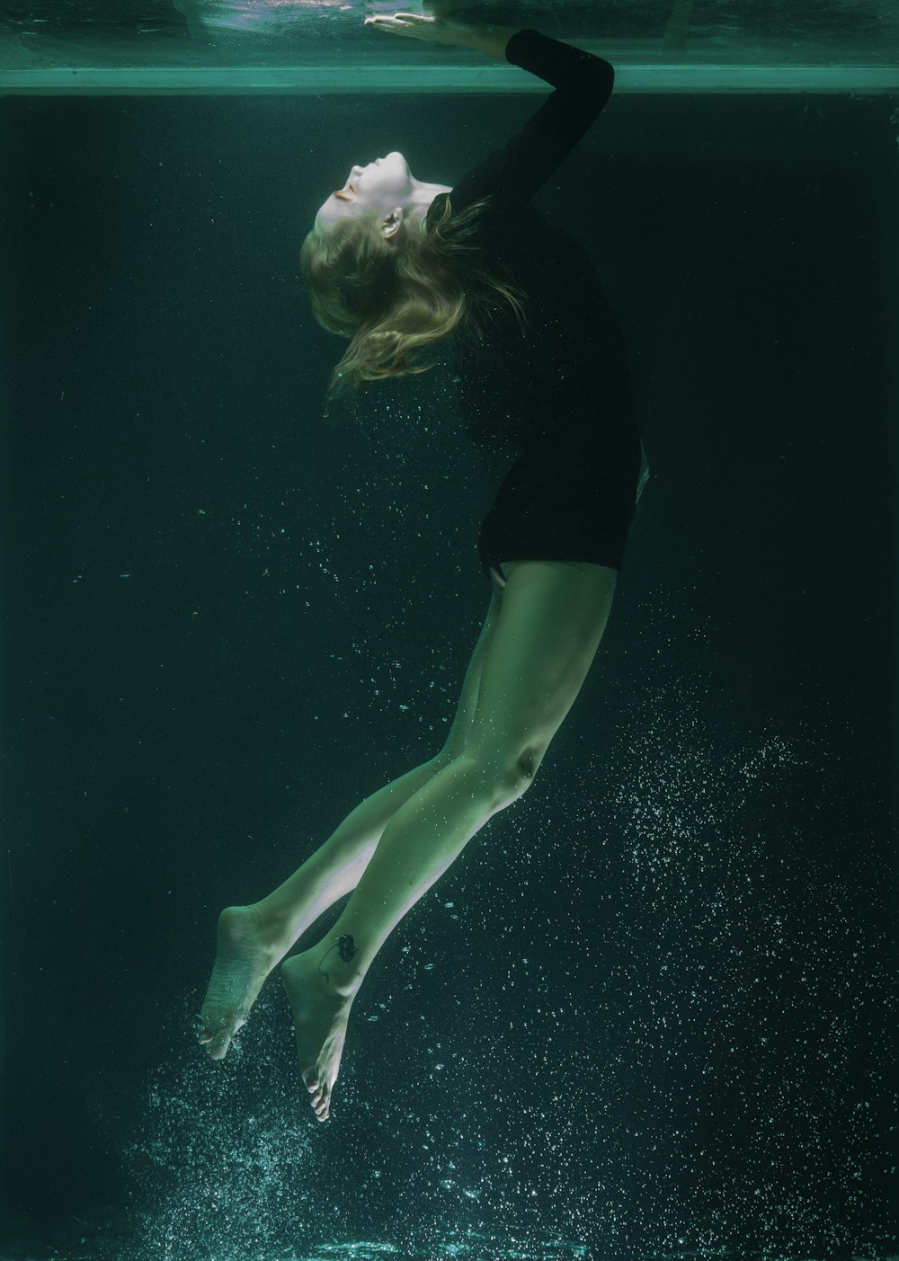 Frau in schwarzem Hemd und grünen Shorts im Wasser