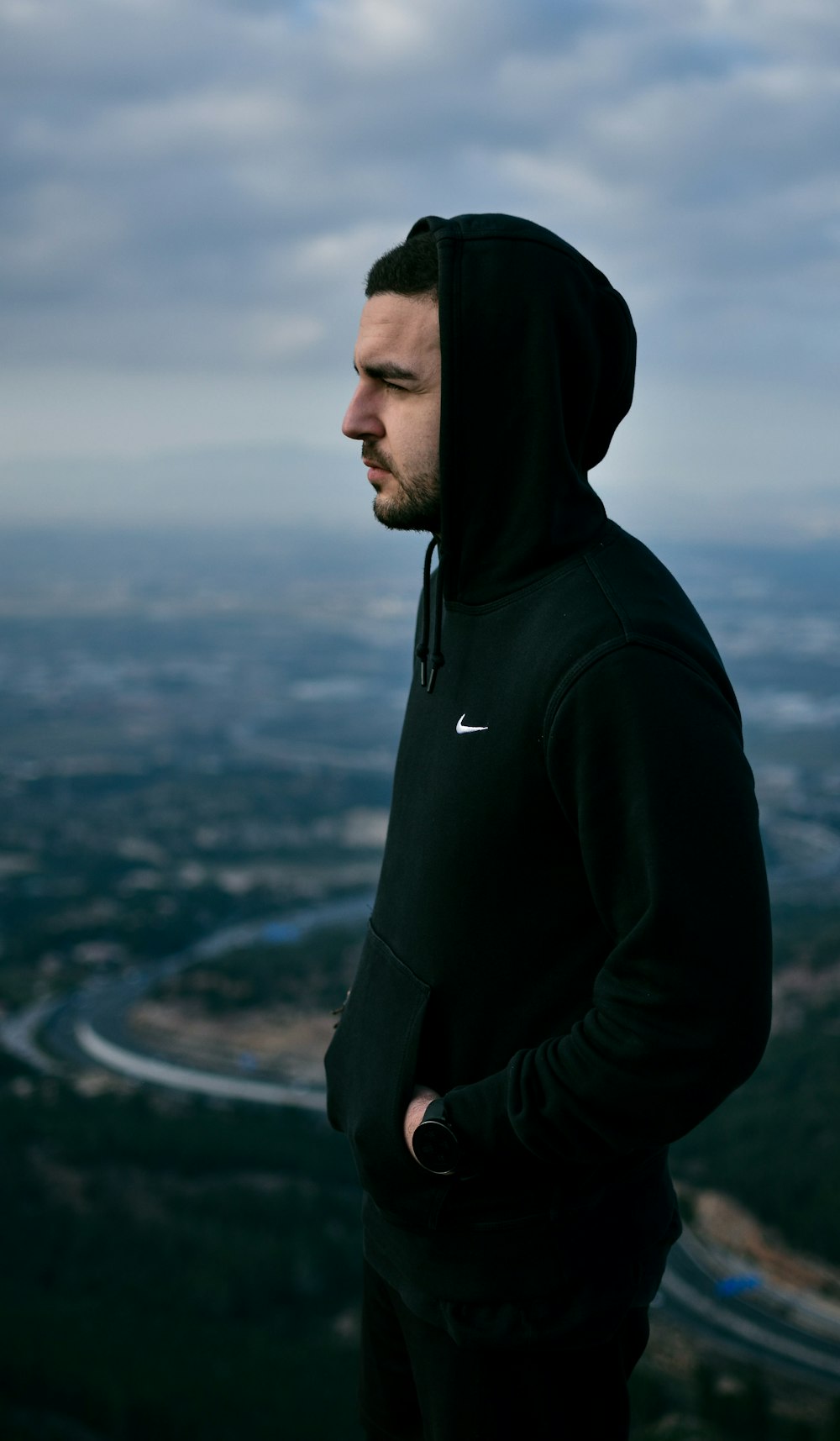 man in black nike hoodie standing on top of building during daytime