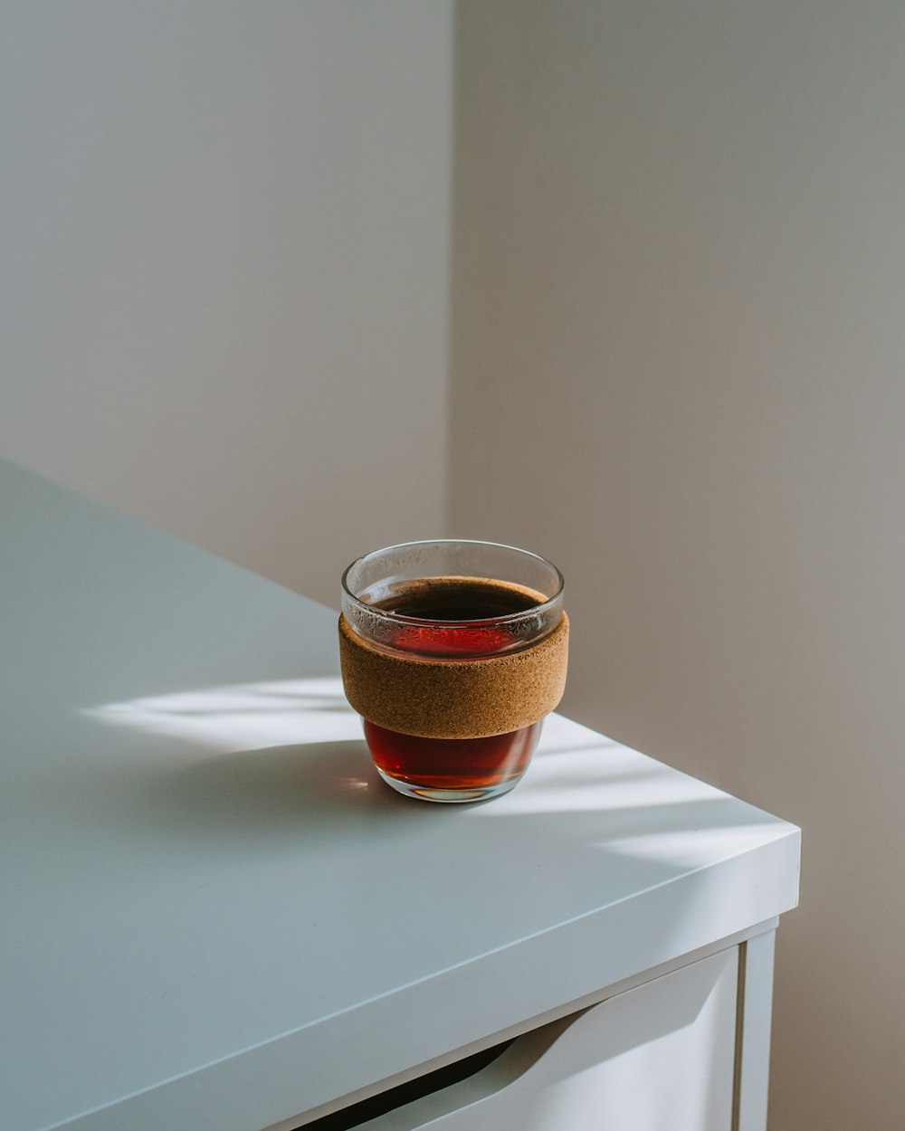 tazza di vetro marrone su tavolo bianco