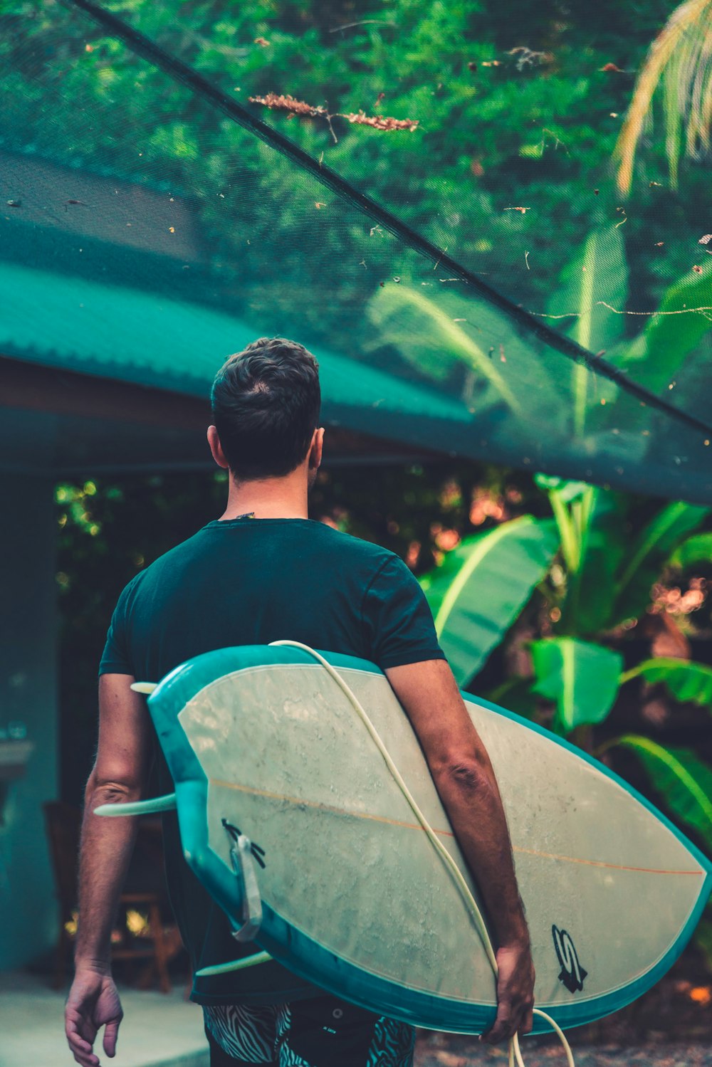 man in purple and blue crew neck shirt holding white surfboard