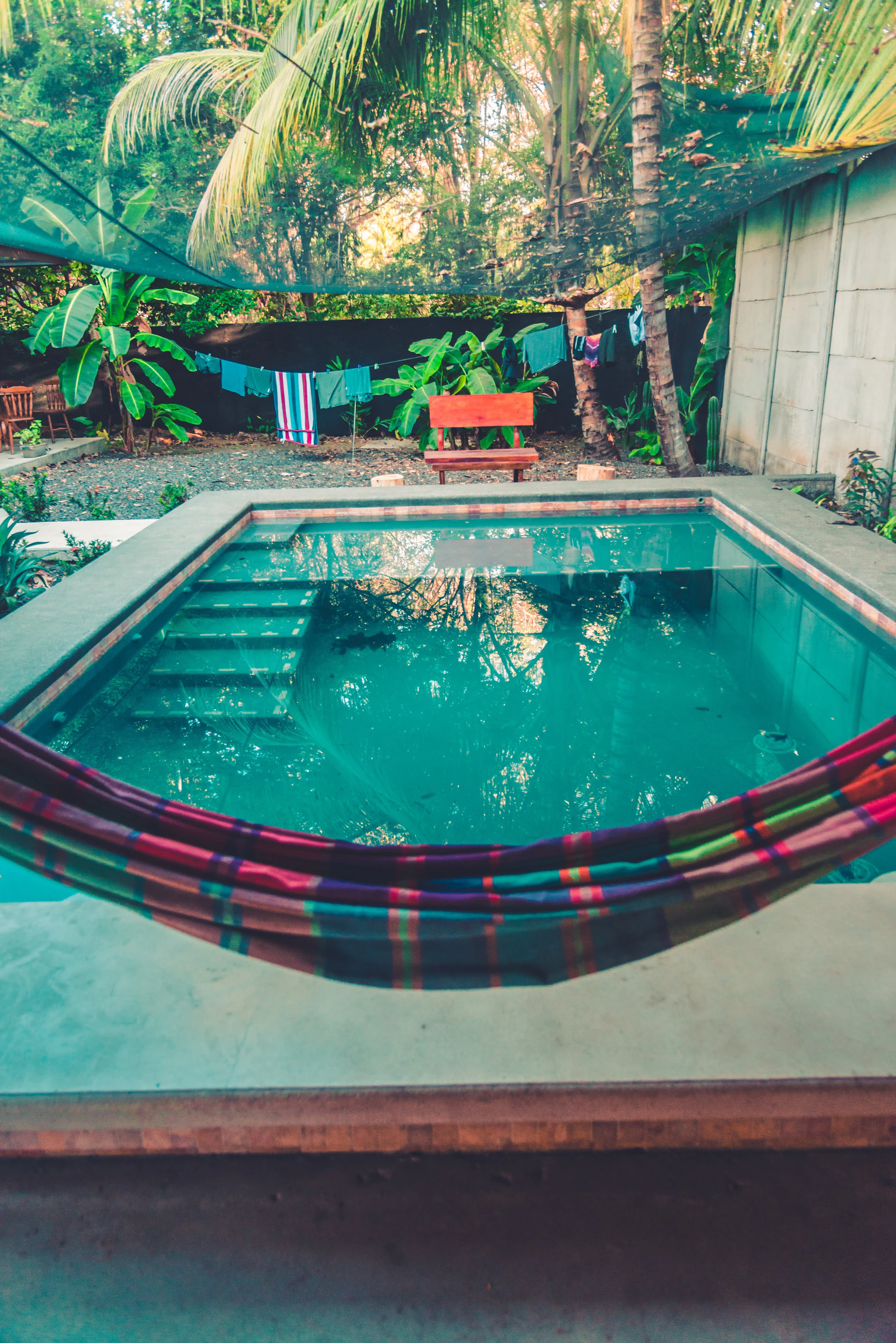 The inviting private pool surrounded by tropical plants and a comfortable terrace with hammocks.