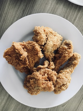 a white plate topped with fried food on top of a wooden table