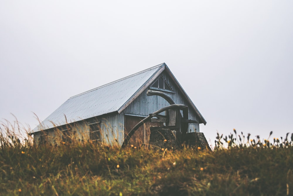 gray wooden house on green grass field under white sky during daytime