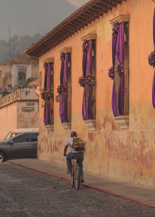 man in black jacket and black pants standing beside pink and yellow painted wall during daytime in Antigua Guatemala Guatemala