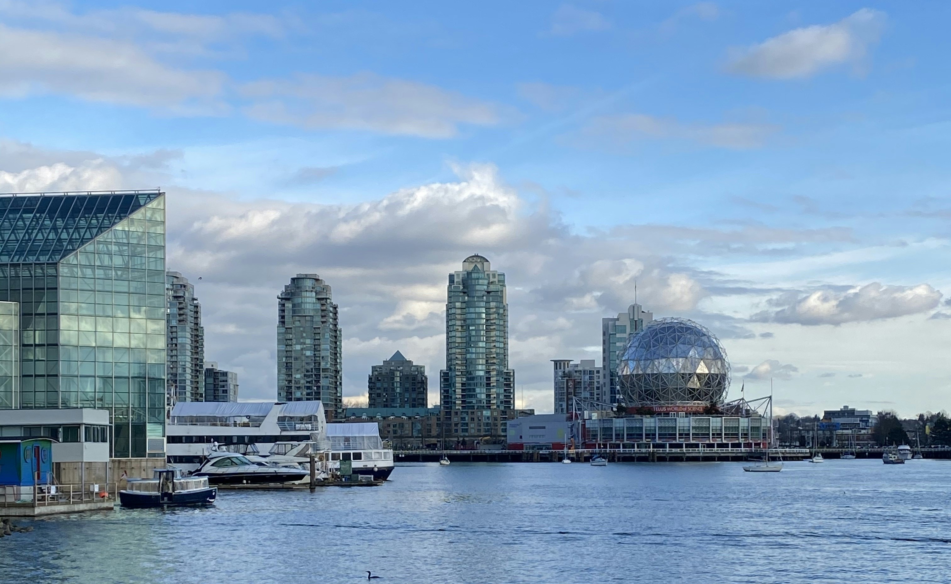 white boat on body of water near city buildings during daytime