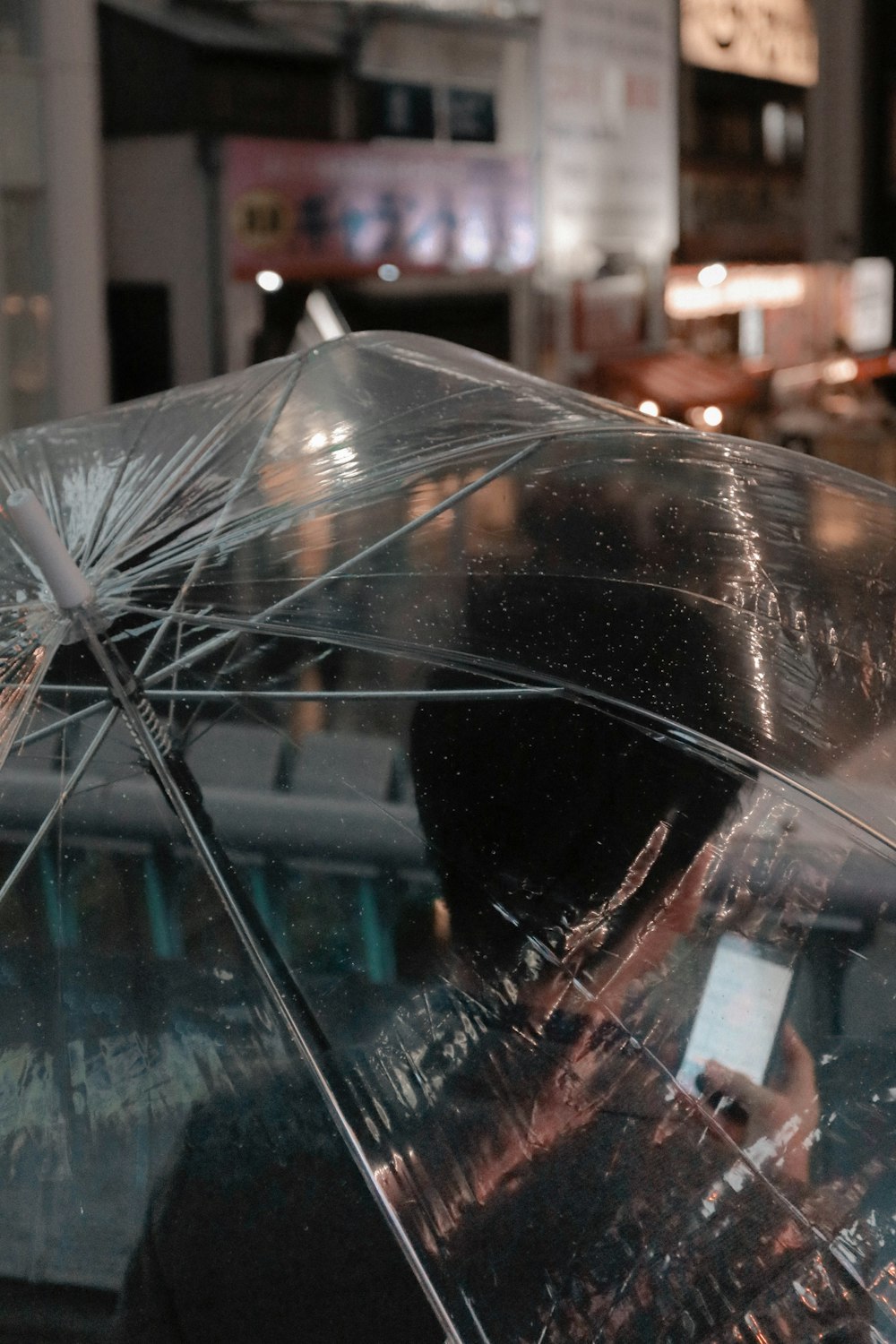 clear umbrella in front of city buildings during night time