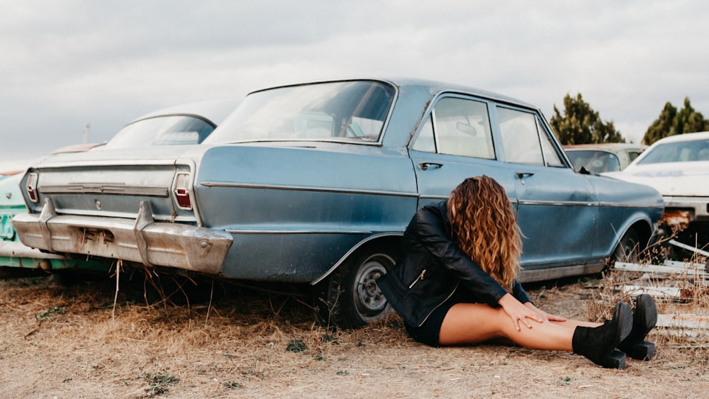 woman in black jacket leaning on teal car