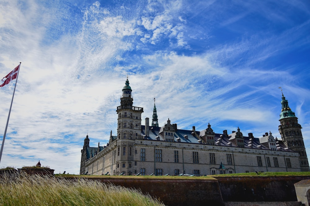 Graues Betongebäude unter blauem Himmel und weißen Wolken tagsüber