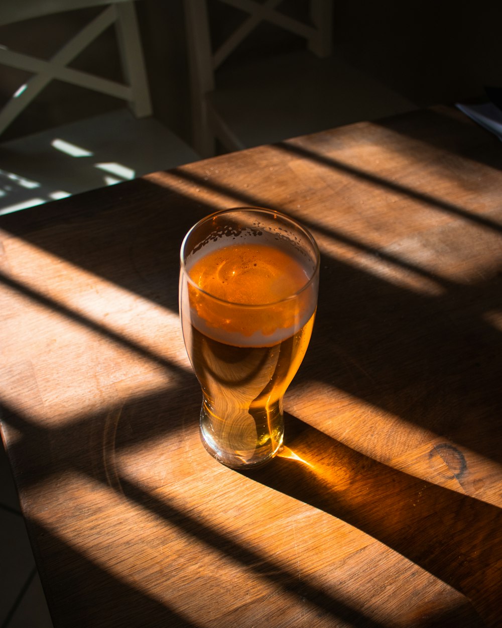 vidro transparente com líquido marrom na mesa de madeira marrom