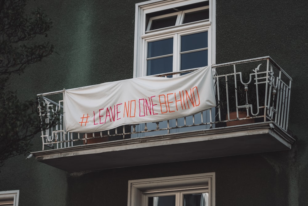 a banner that reads leave to one behind on a balcony