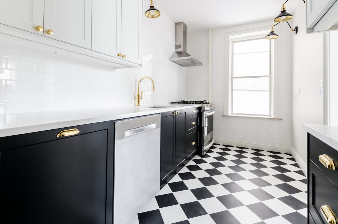 White & Black kitchen with gold faucets and gold finishings. Black & white checkered floor. Marble countertop. Black kitchen cabinets. White kitchen cabinets.