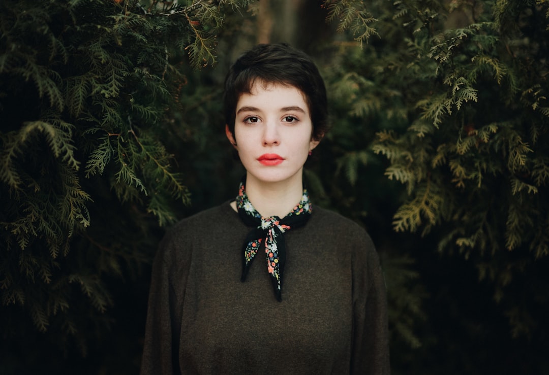 woman in black turtleneck sweater standing near green trees during daytime