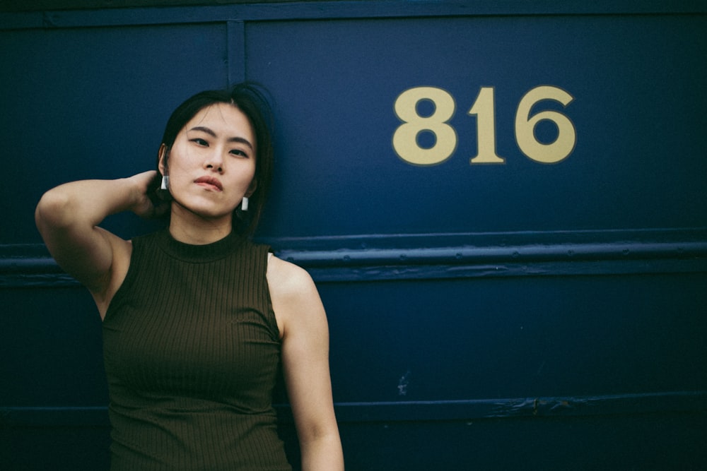 woman in black tank top standing beside blue wall